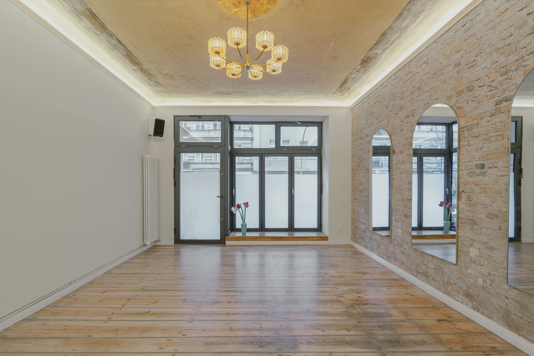 The empty InSketch venue with wooden floors, large front windows and an exposed-brick mirror wall
