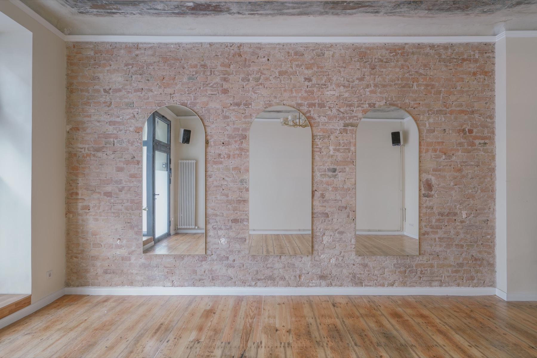 Three arched mirrors on the exposed-brick wall inside the empty InSketch venue